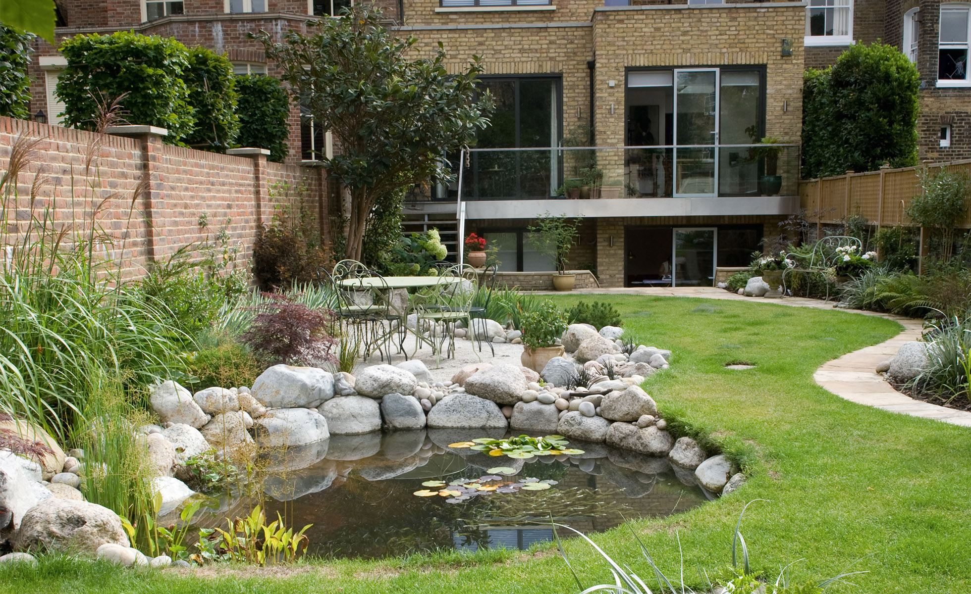 Front yard landscaping with lush planting beds around a boulder-edged pond and a curving green lawn in the San Fernando Valley