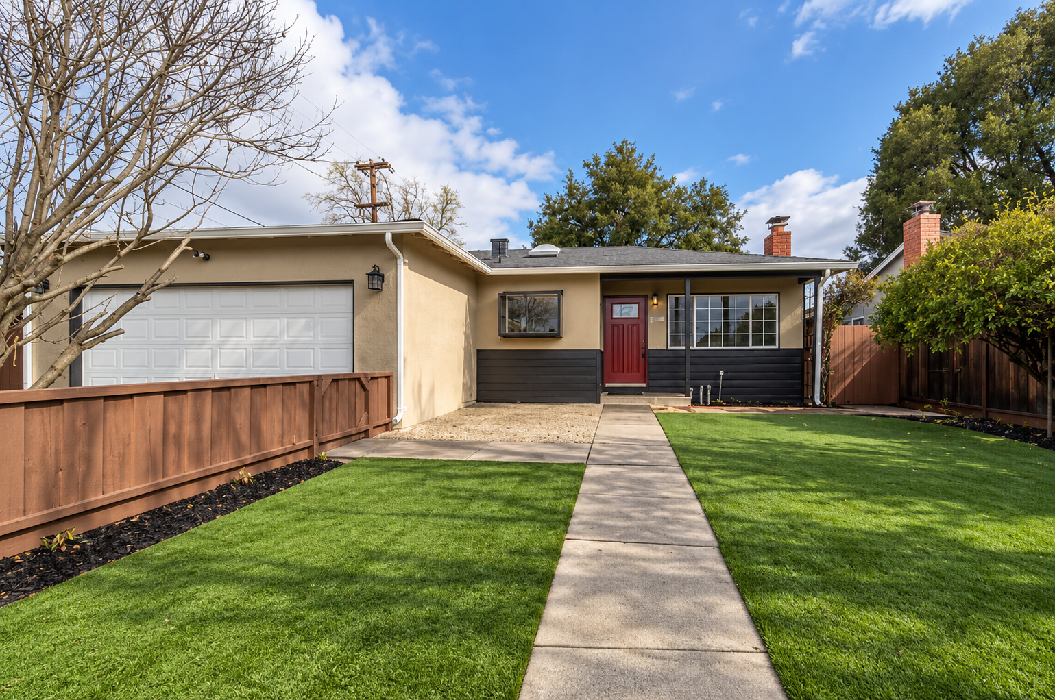 Front yard landscaping at a mid-century ranch home with a neat lawn, gravel bed, and wooden fence in the San Fernando Valley