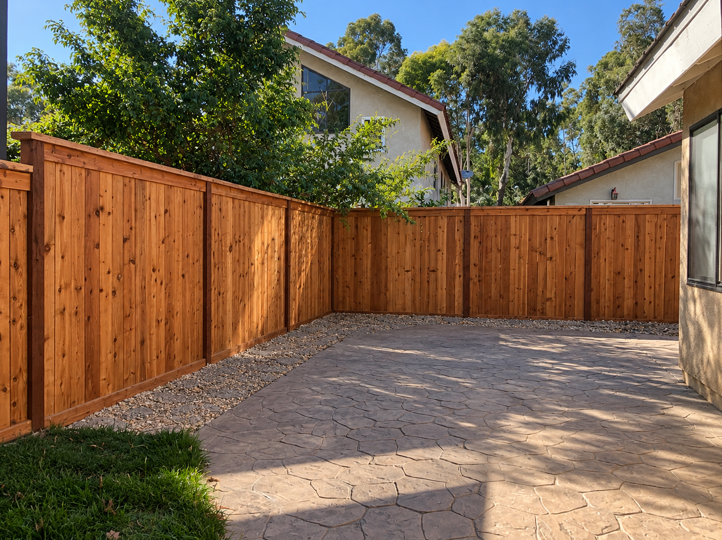 Wooden privacy fencing enclosing a stamped concrete patio in a sunny backyard in the San Fernando Valley