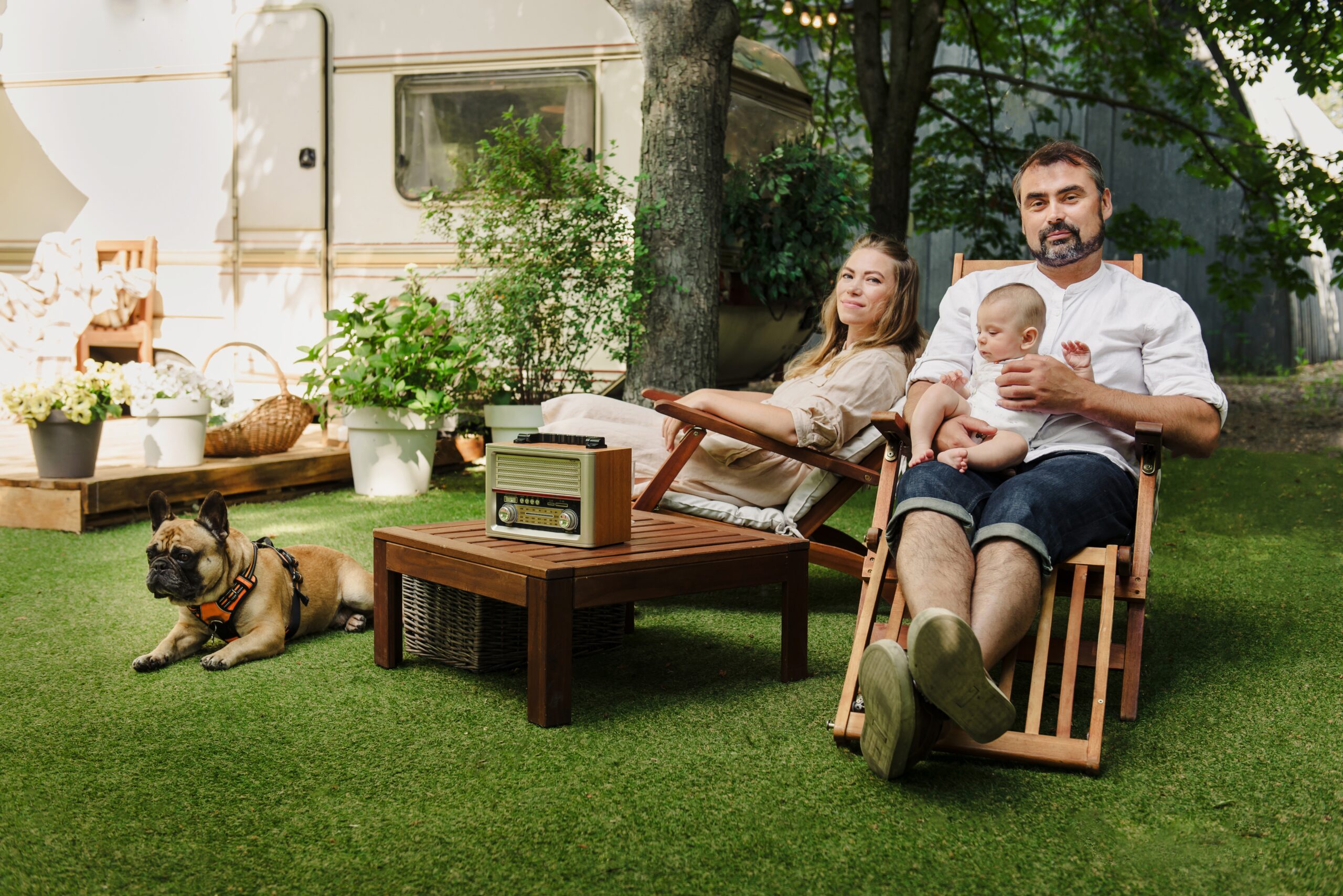Family with a baby and their dog relaxing on lounge chairs in an outdoor seating area, a hardscape design project in the San Fernando Valley