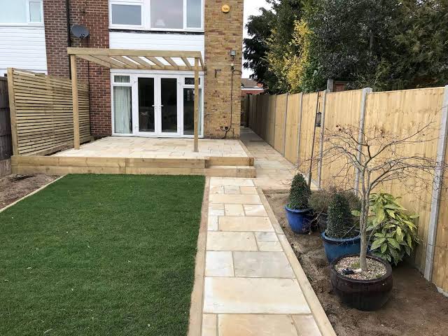 Front yard landscaping with a stone paver walkway running beside a green lawn toward a raised patio in the San Fernando Valley