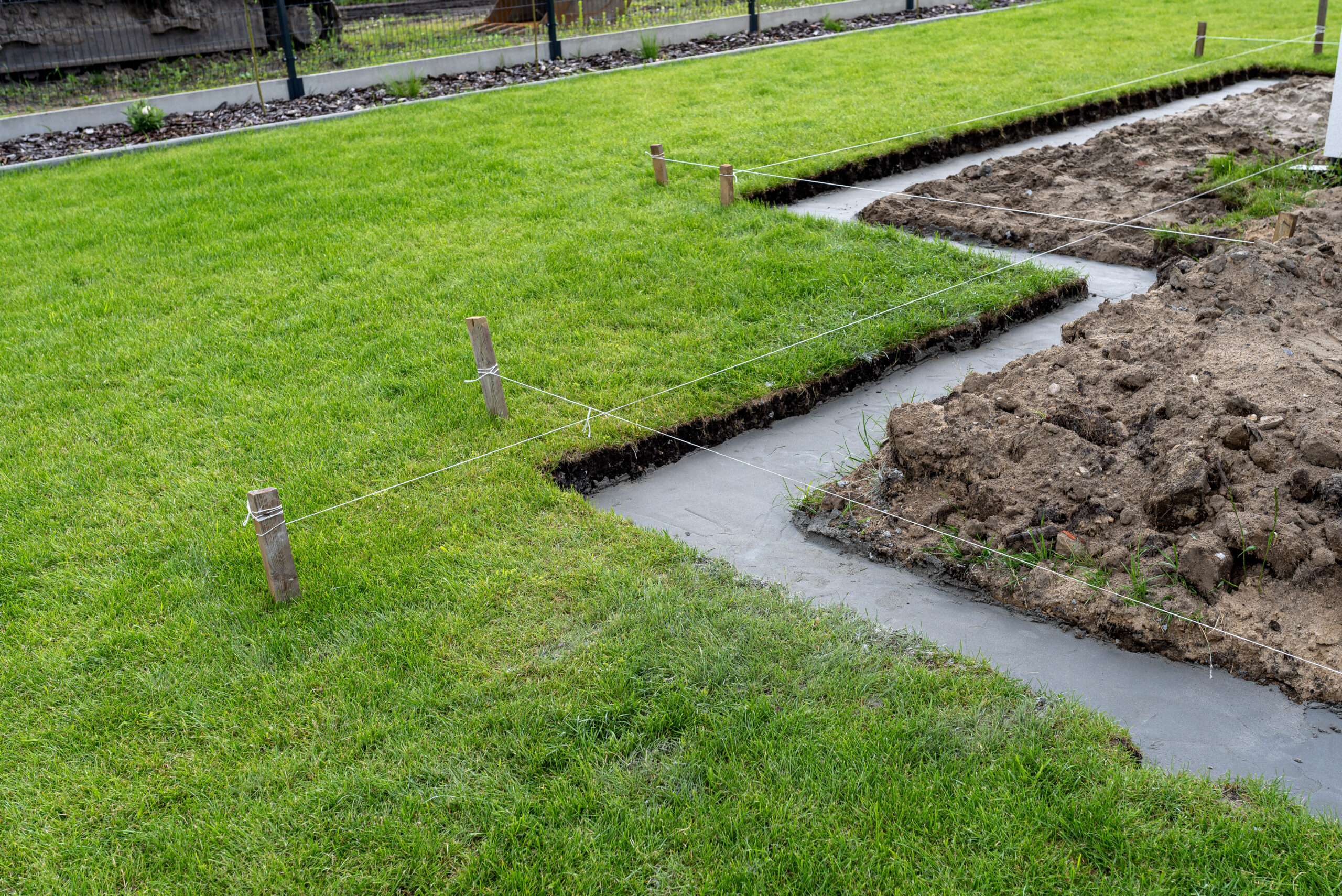 Landscaping groundwork with concrete footings poured in a trench marked out across a lawn in the San Fernando Valley