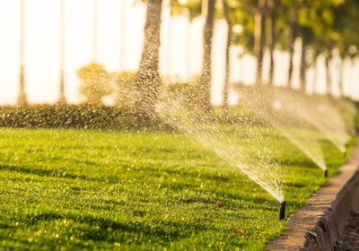 Irrigation sprinklers watering a green lawn in warm evening light in the San Fernando Valley