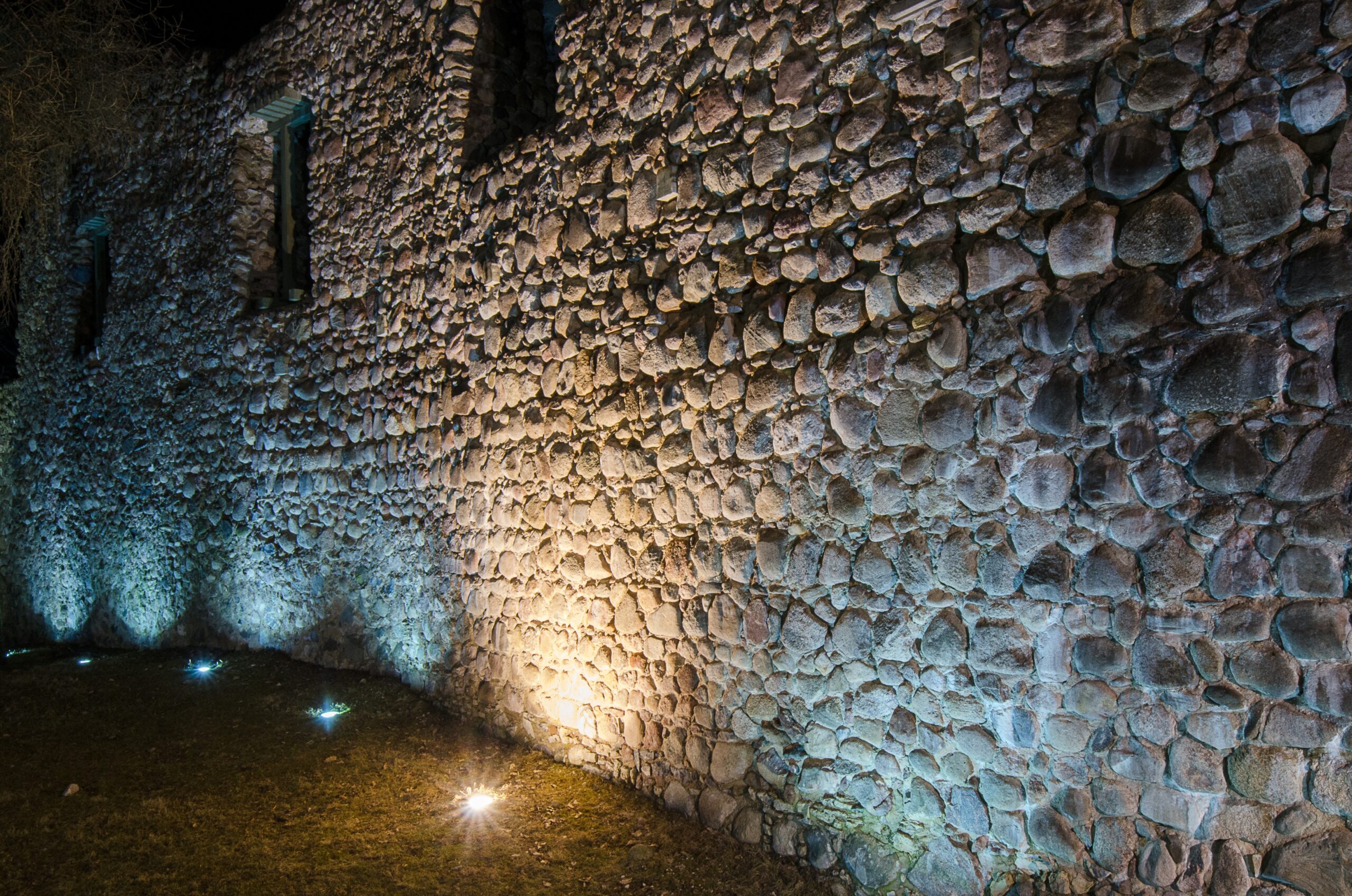 Landscape lighting uplights washing over a tall rustic stone wall at night in the San Fernando Valley