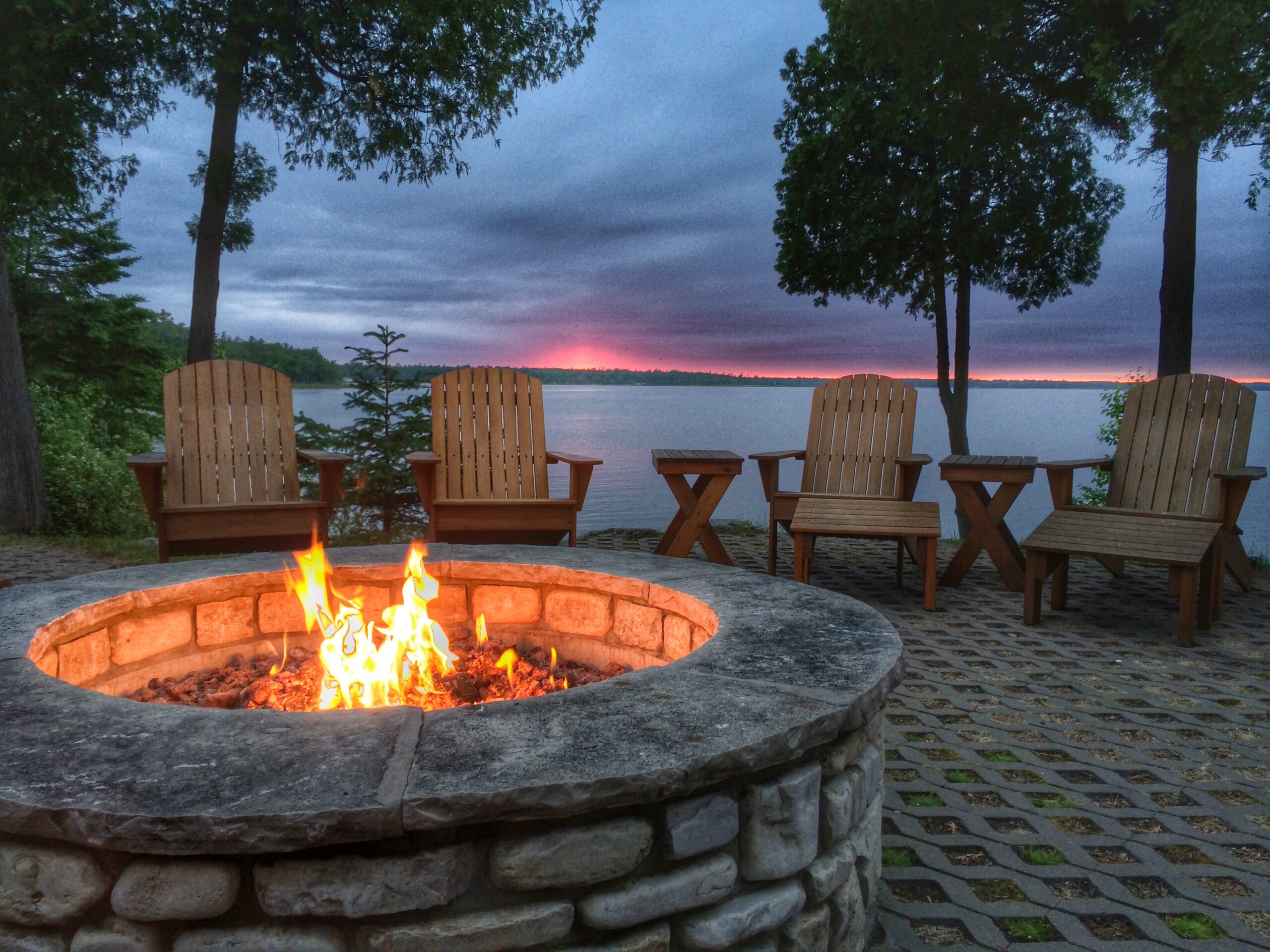 Fire pit burning at sunset beside a lake, a fire feature built as part of a hardscape design project in the San Fernando Valley
